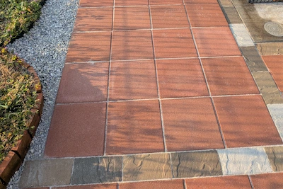 オレンジ色の平板と多色の石材を組み合わせ雑草対策と美観を両立させたお庭のアプローチ